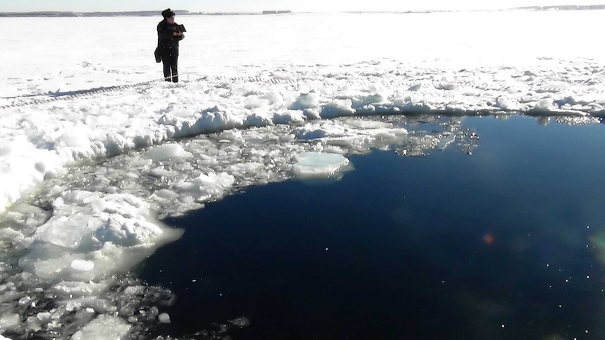 Russian police stand by hole in frozen lake