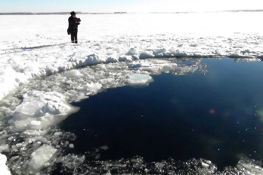 Russian police stand by hole in frozen lake reportedly caused by meteor