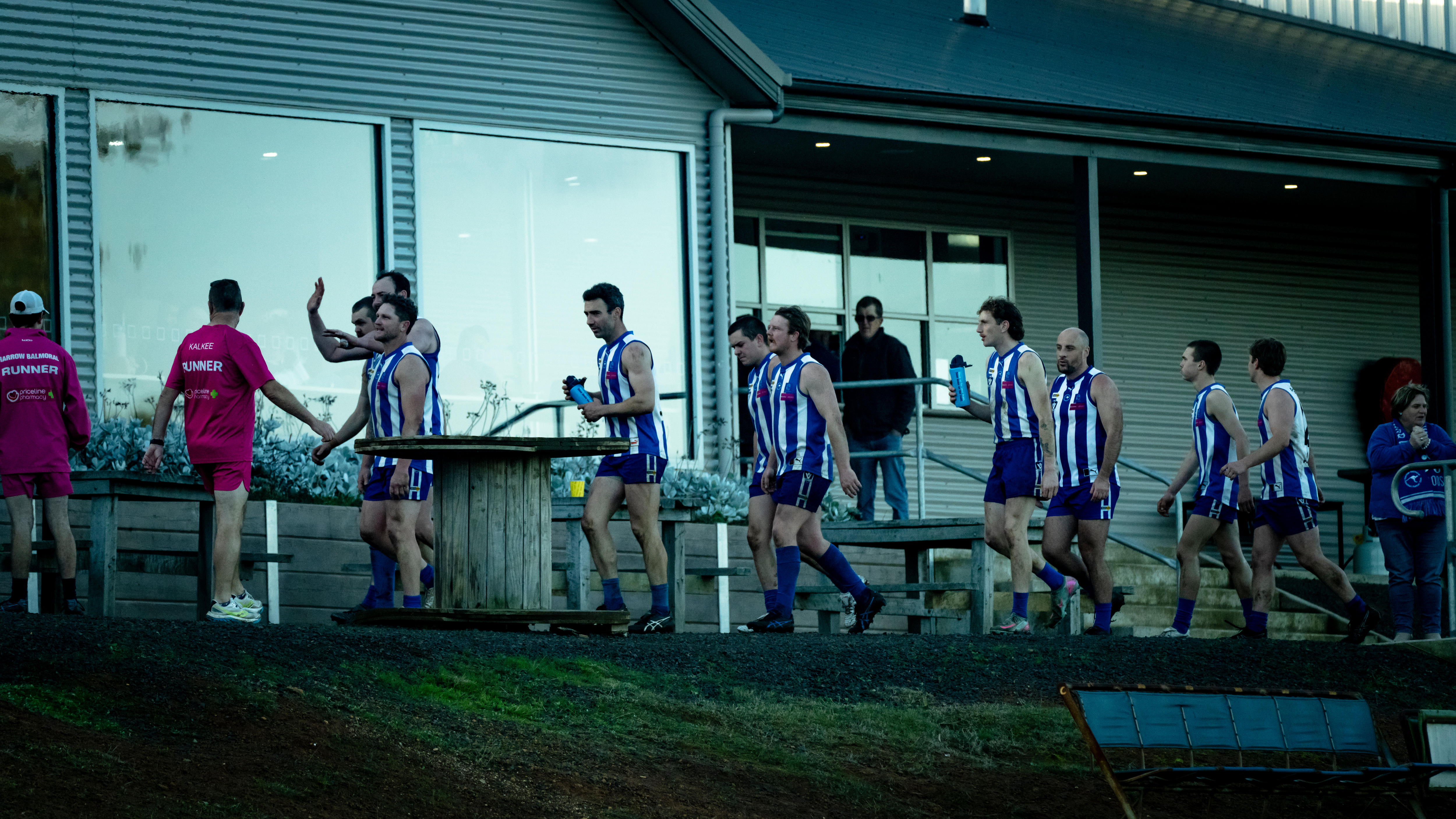 Footballers walk with a building behind them.