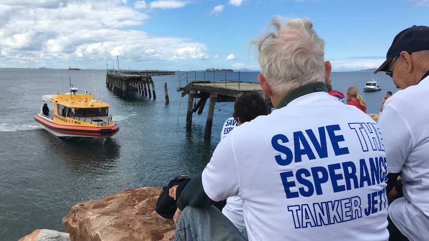 Protesters look on at ageing wooden jetty