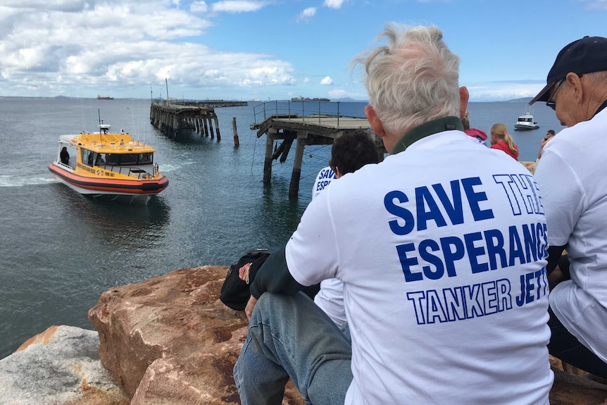 Protesters look on at ageing wooden jetty.