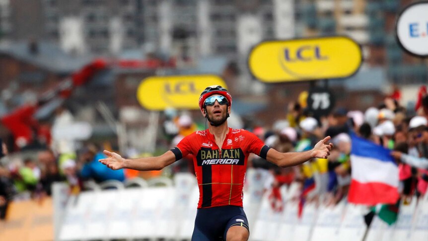 Vincenzo Nibali puts both arms up in the air as he rides over the finish line