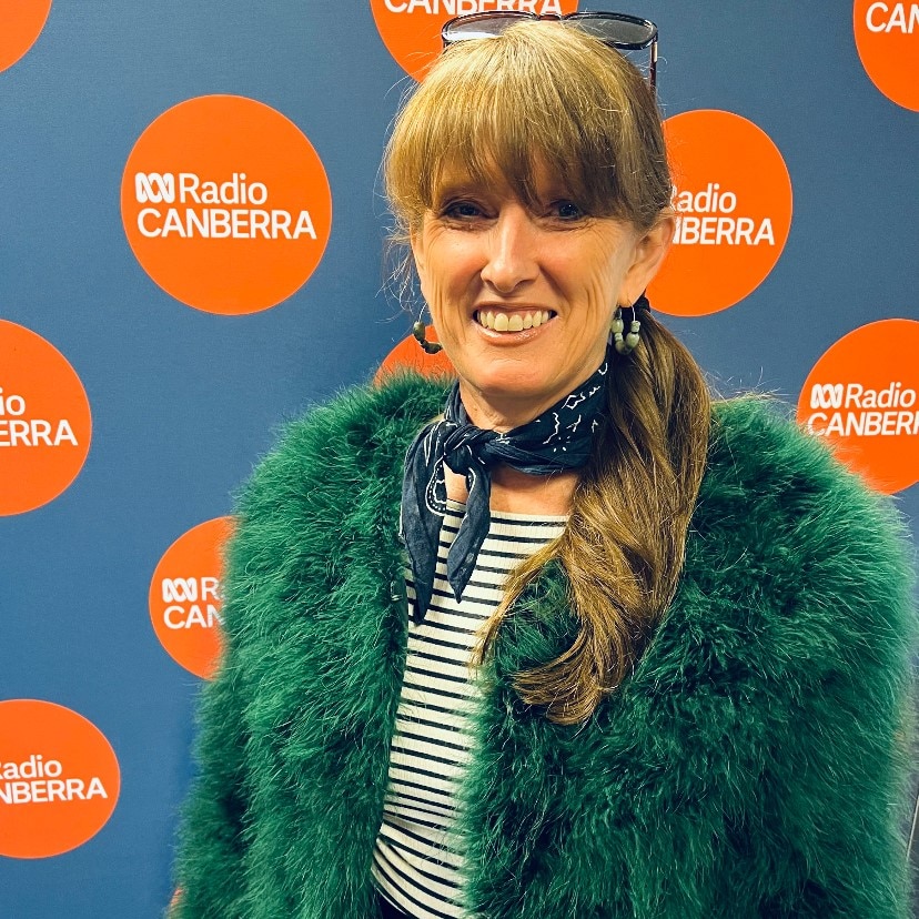 Fashion designer Kelli Donovan smiles in front of ABC Radio Canberra backdrop