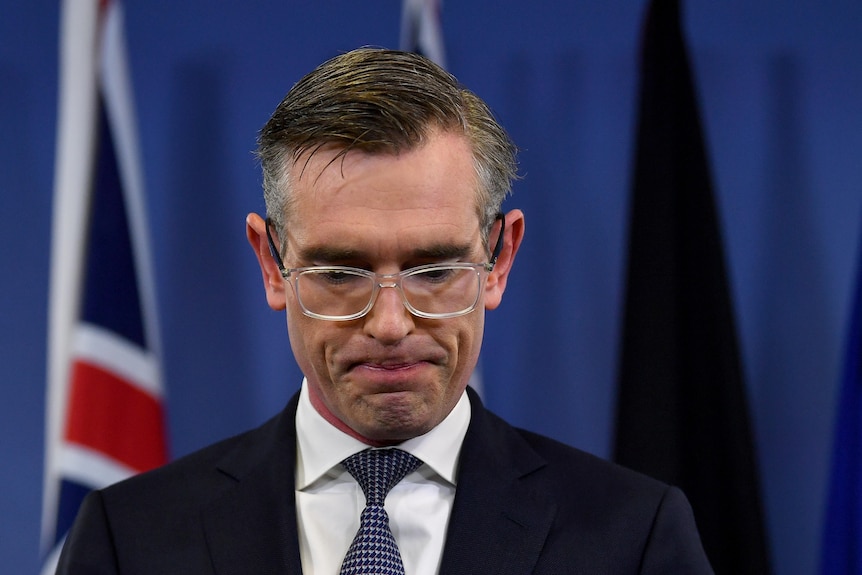 Dominic Perrottet looks down while speaking at a press conference