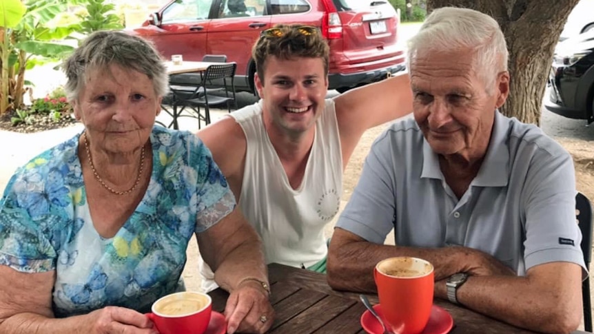 A woman sits at an outdoor table with two men.