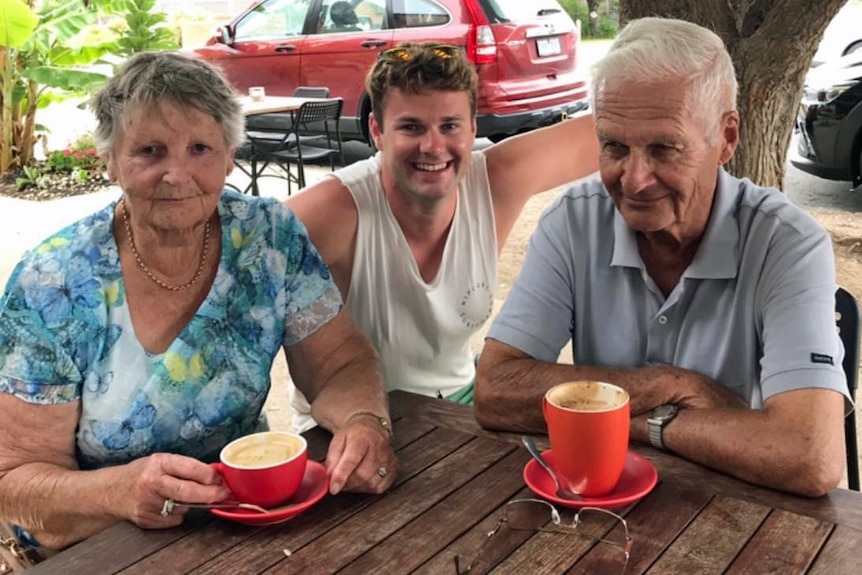 A woman sits at an outdoor table with two men.