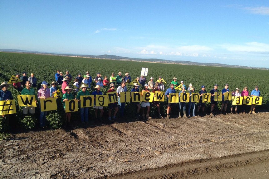 Young farmers hold up small signs spelling out '#WrongMineWrongPlace'