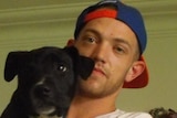 A man in a cap holding a dog
