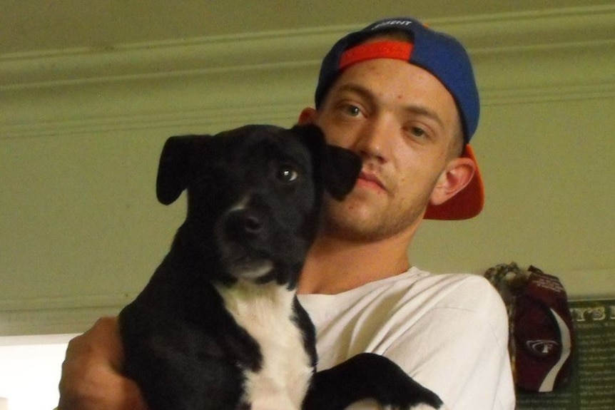 A man in a cap holding a dog