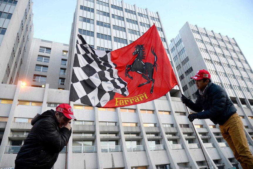 Fans hold a Ferrari flag outside the Grenoble University Hospital Centre in the French Alps.