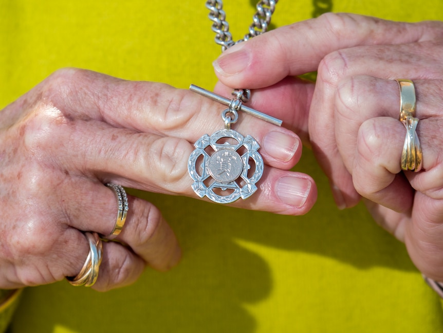 Woman's hands holding a pendant imprinted with Chinese writing character.