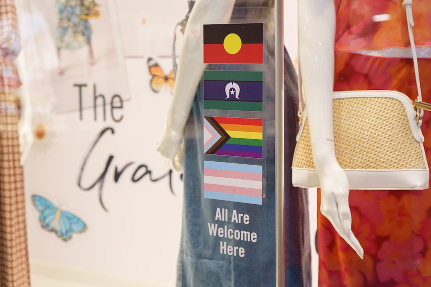 Stickers on a storefront bearing the trans, LGBT, Aboriginal, and Torres Strait Islander flags.