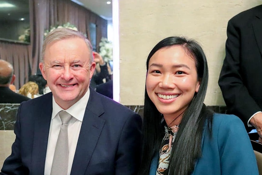 An older white man and a young Asian woman smile for the camera.