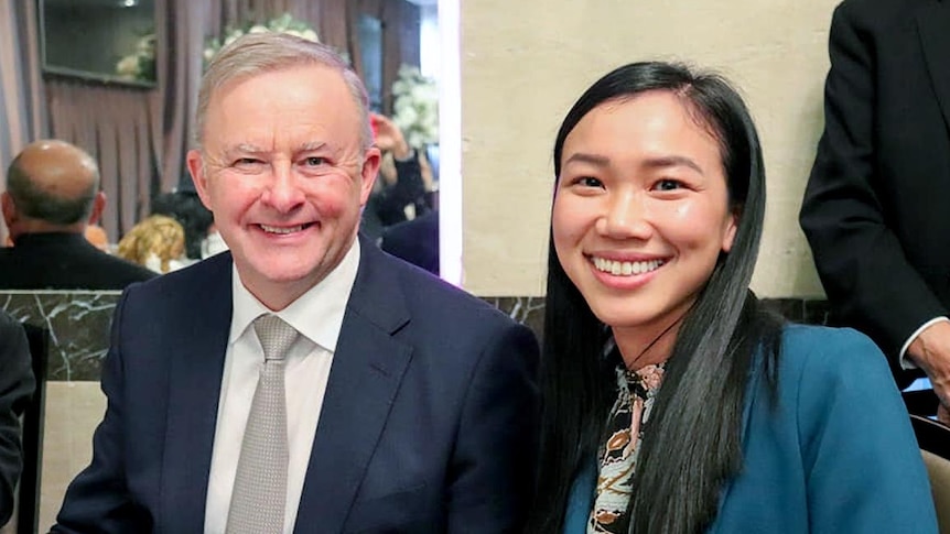 An older white man and a young Asian woman smile for the camera.