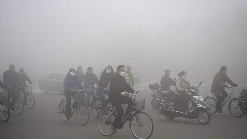People ride along a street on a smoggy day in Daqing, Heilongjiang province