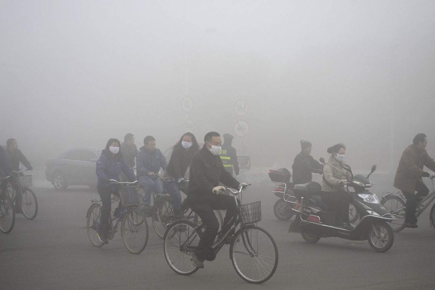 People ride along a street on a smoggy day in Daqing, Heilongjiang province