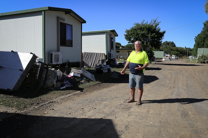 Graeme Bolton stands next to flood-damaged cabins