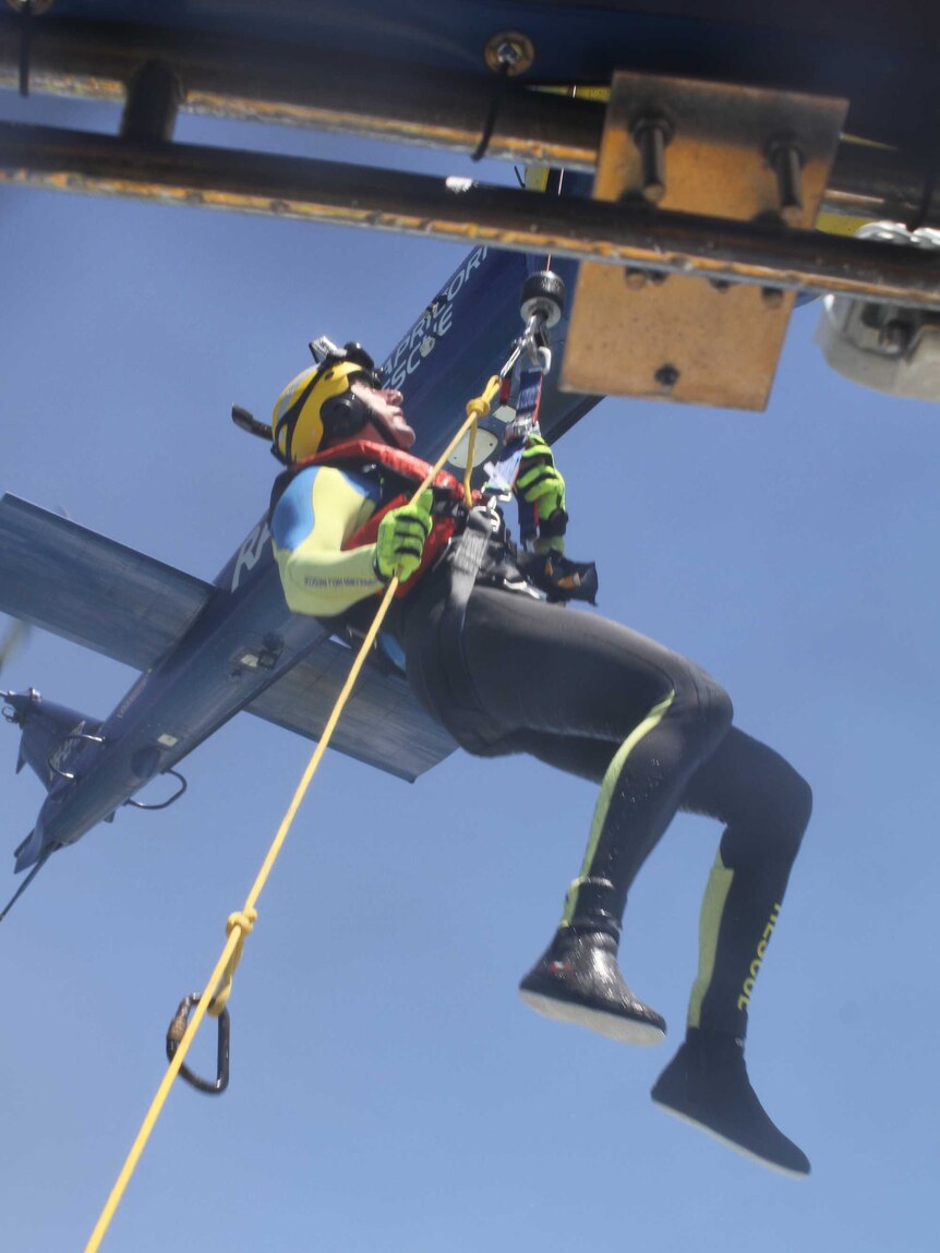 man being lowered from helicopter