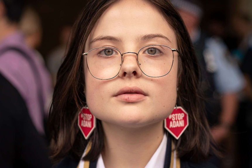 Daisy Jeffrey looks at the camera from close range wearing 'Stop Adani' earrings.