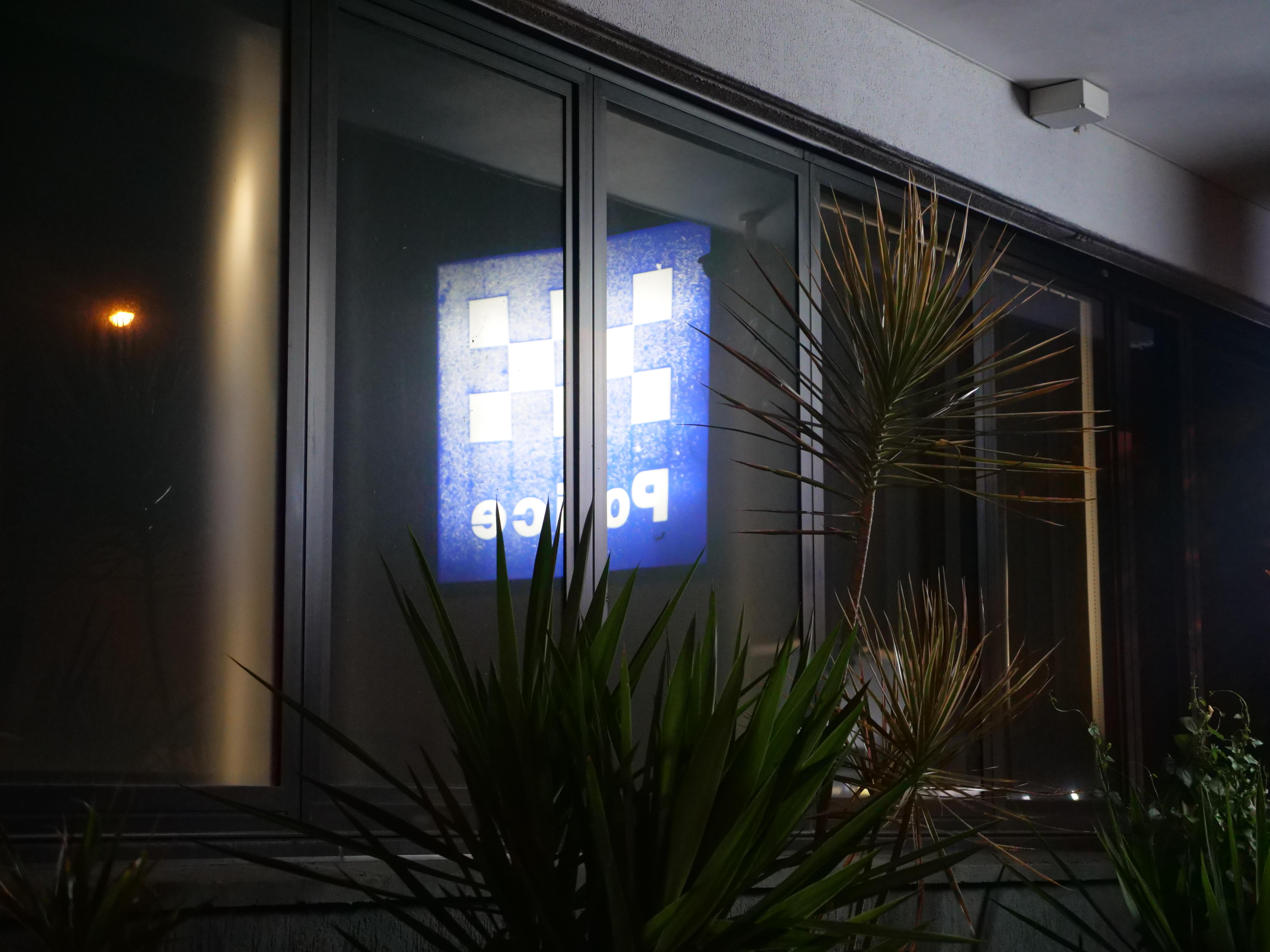 Un letrero policial brillante gira cuando se ve a través de una ventana cercana por la noche