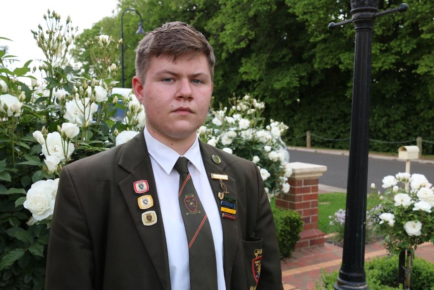 A young man in school uniform outdoors