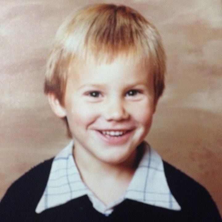 A young boy with blonde hair smiles.