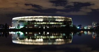 Perth Stadium at night reflected in the Swan River.