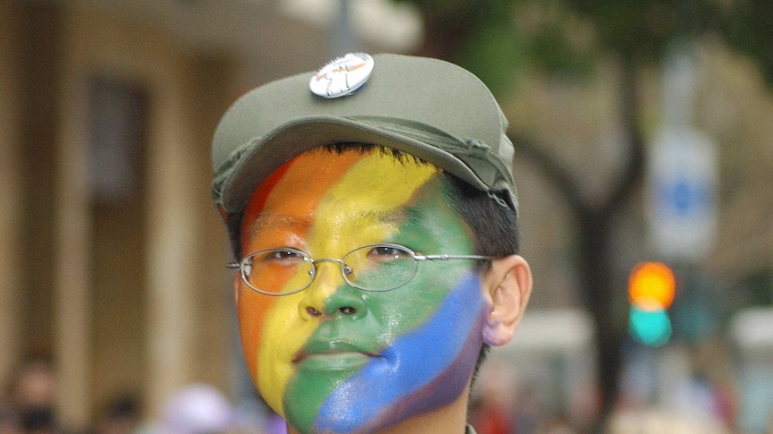 A man in a soldier's outfit waves a rainbow flag while marching in a gay pride parade in Taipei, 13 October 2007.