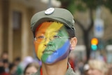 A man in a soldier's outfit waves a rainbow flag while marching in a gay pride parade in Taipei, 13 October 2007.