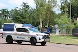 A NT Police vehicle parked in a suburban street on a sunny day, with police tape in the background.
