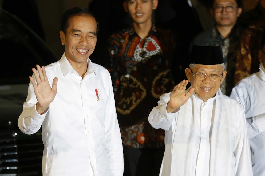 Joko Widodo and his running mate Ma'ruf Amin wave to a crowd wearing white suits.
