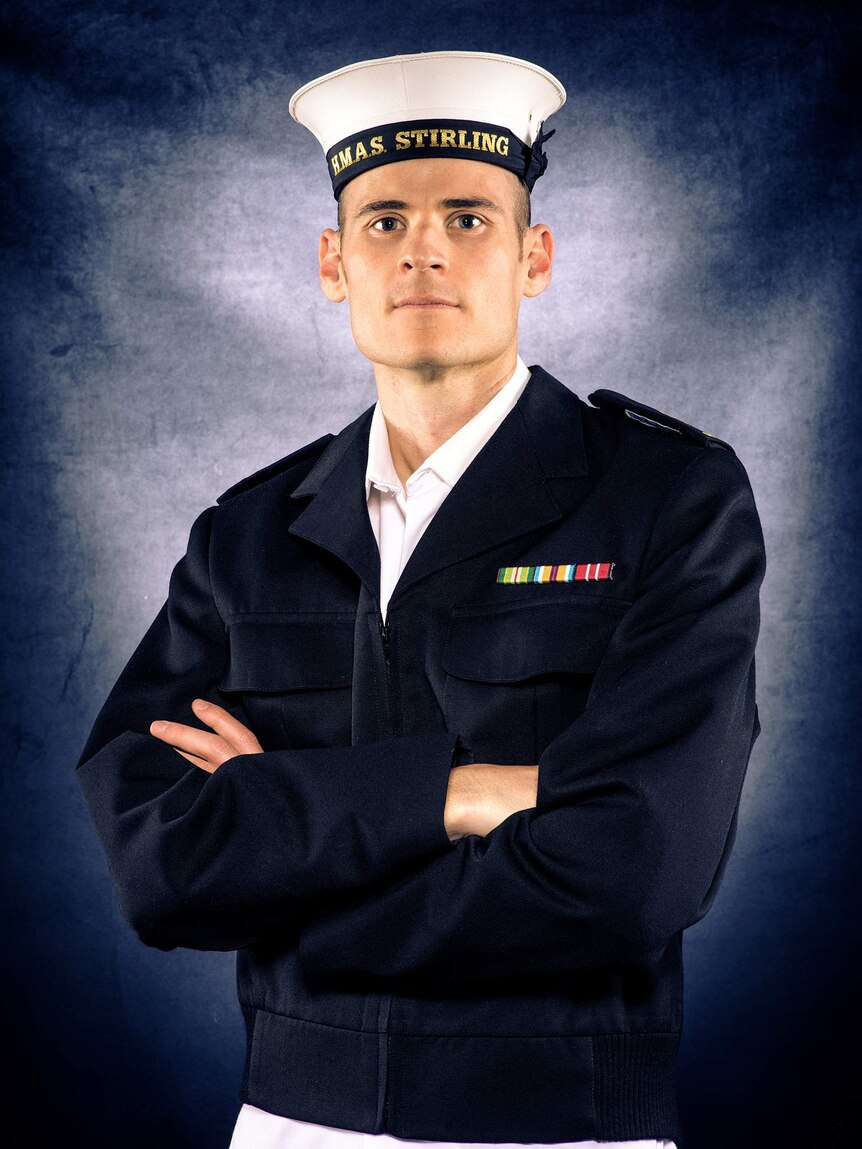 A man in a sailor uniform in front of a blue background.