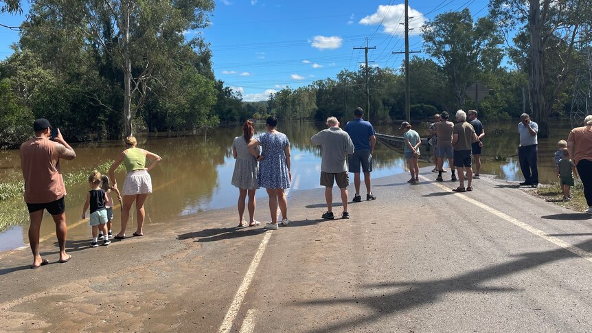 A group of people watching a flood across a road.