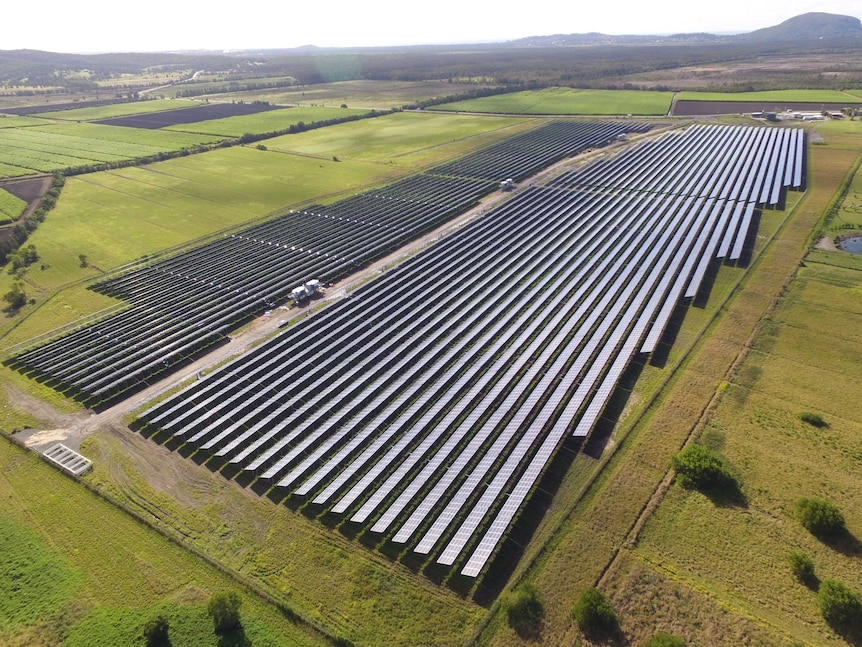 Many rows of 57,850 solar panels with grass paddocks and rural land in the background.