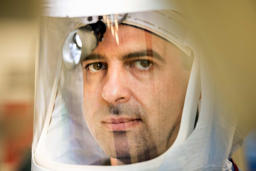 A close-up head shot of AMA president Omar Khorshid wearing a full protective face helmet for surgery.