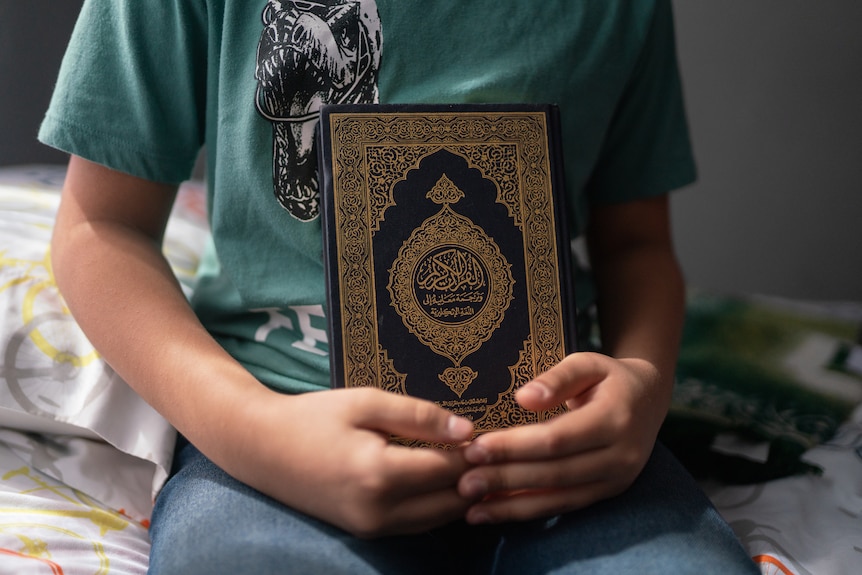 A boy holds a Koran.