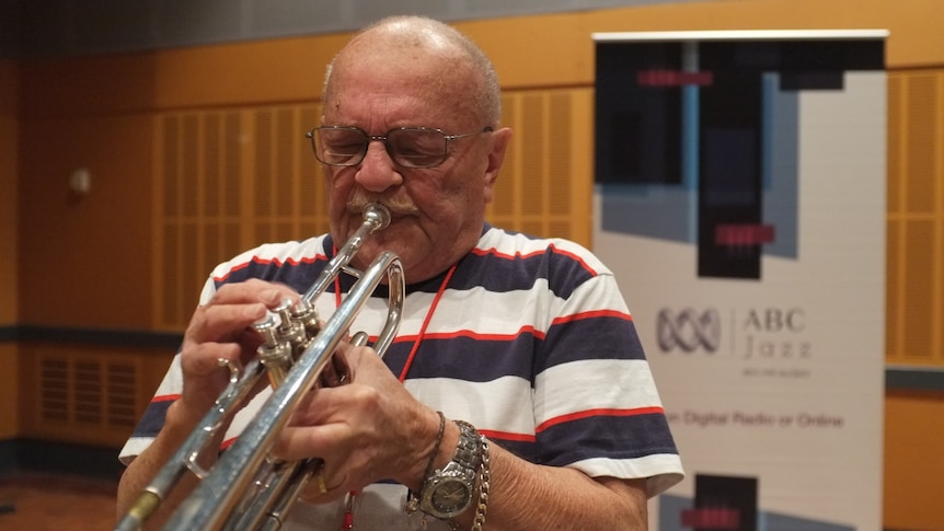 A shot of an elderley Don Rader in the ABC Jazz studio with his silver-toned trumpet and glasses