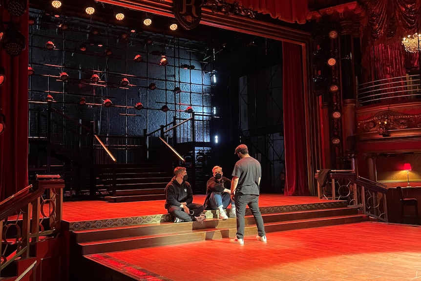 Three men sit on a stage talking