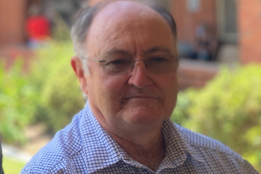 man wearing checked shirt and glasses staring at camera