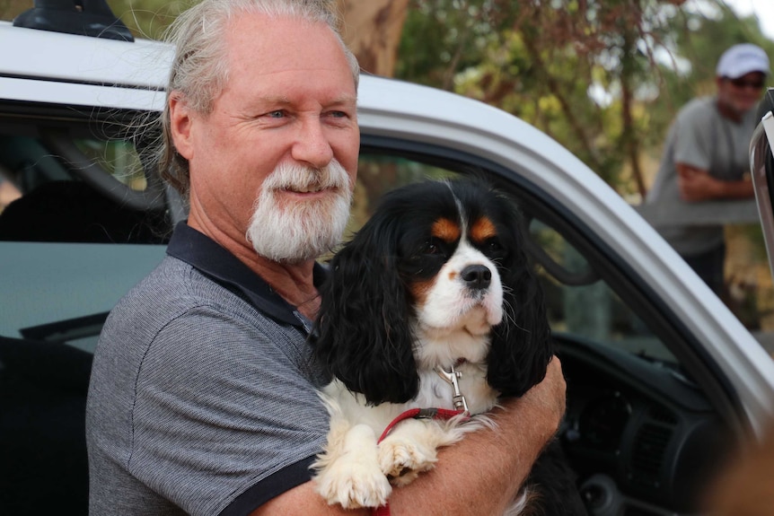 Steve Thomas with his dog in front of a car.