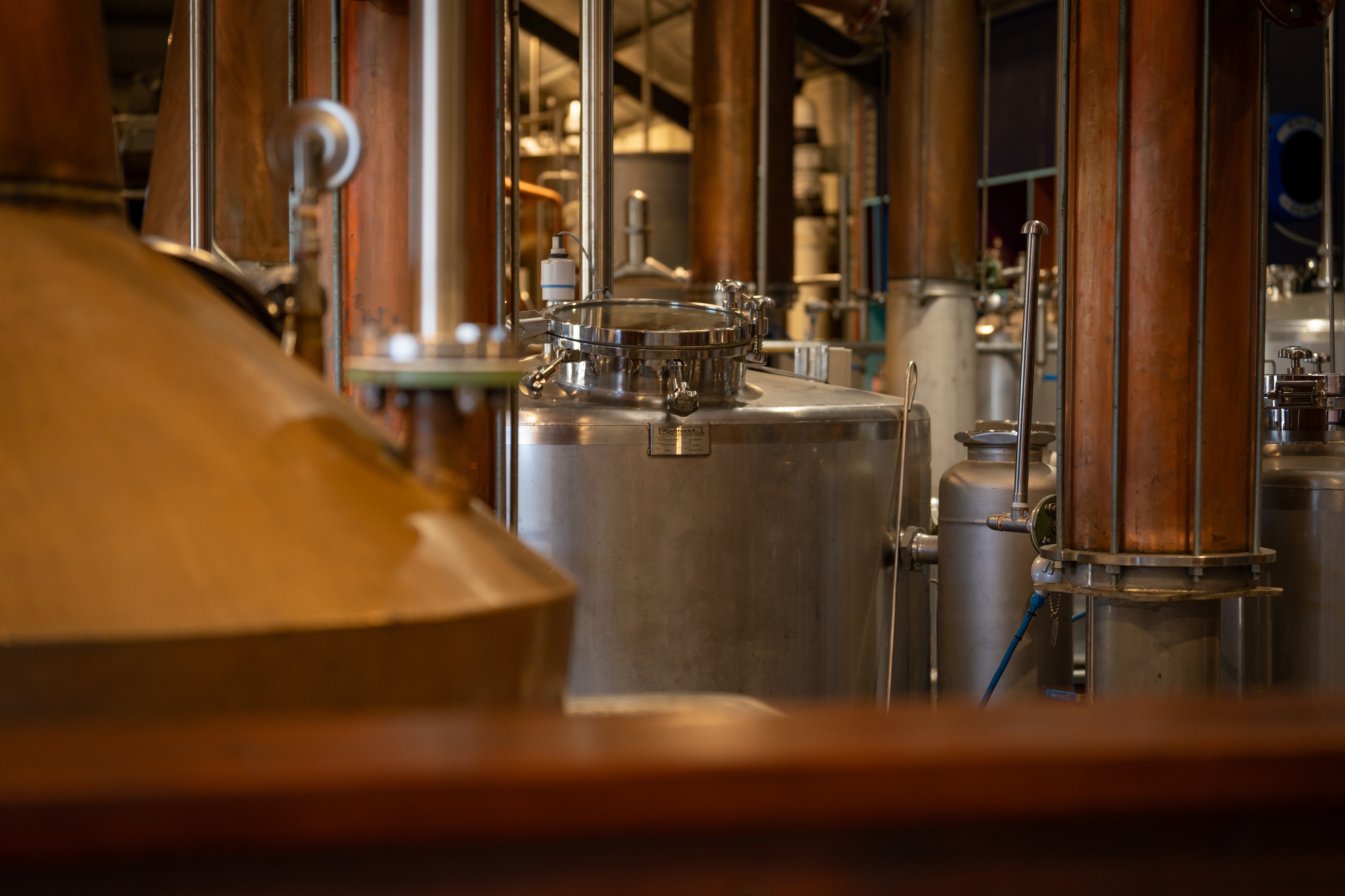 Dusty barrels and a warm coloured copper still in large shed