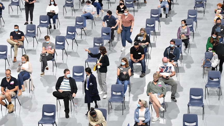 People wait in chairs at a vaccine hub.