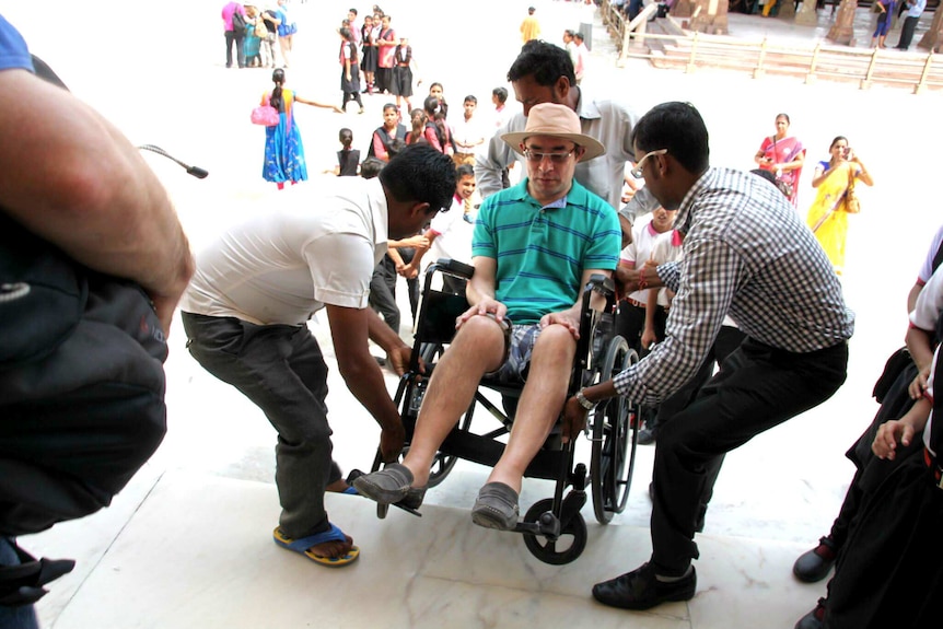 Martin being pulled up stairs by a group of men.