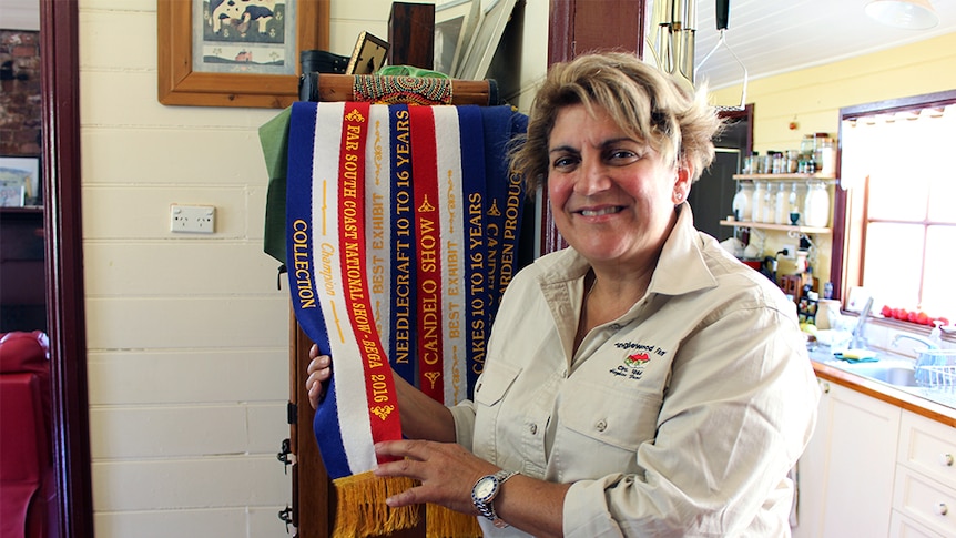 Roxanne Hopkins with her red, white, and blue champion show ribbon for her jam collection.