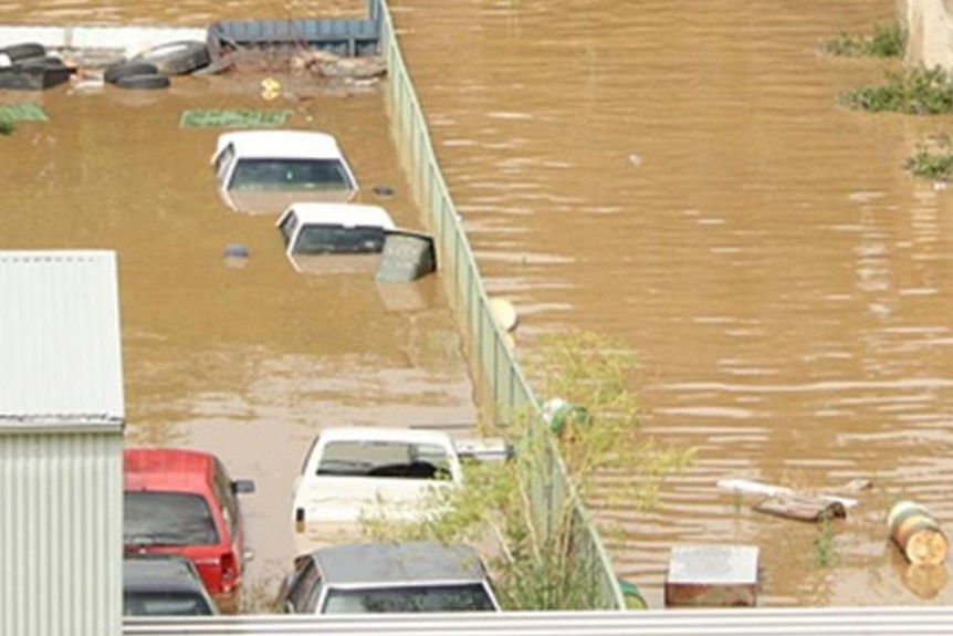 Car windscreens and roofs are visible in brown floodwater.