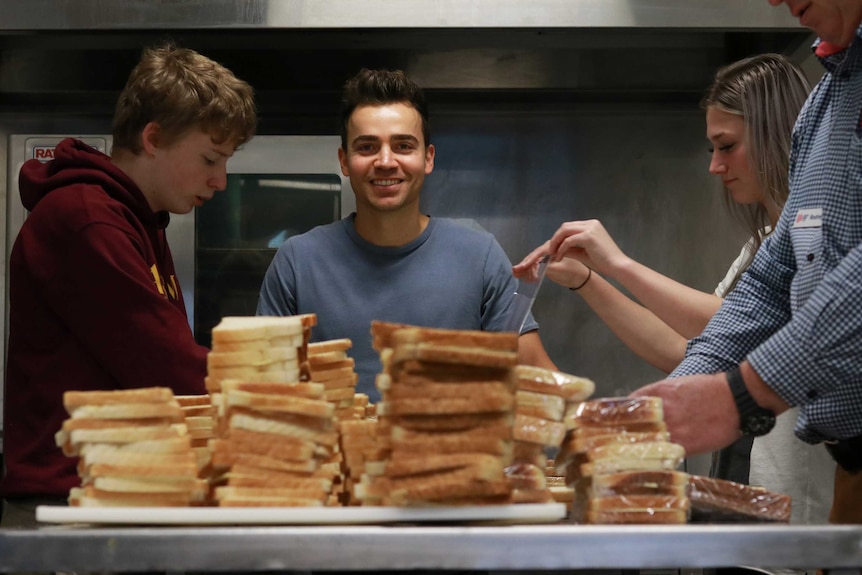 Lyndon Galea standing behind piles of sandwiches