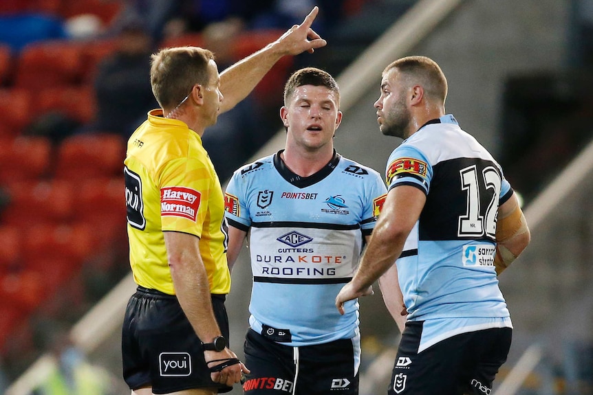 A rugby league player closes his eyes as a referee points to the stands, signalling a send-off.