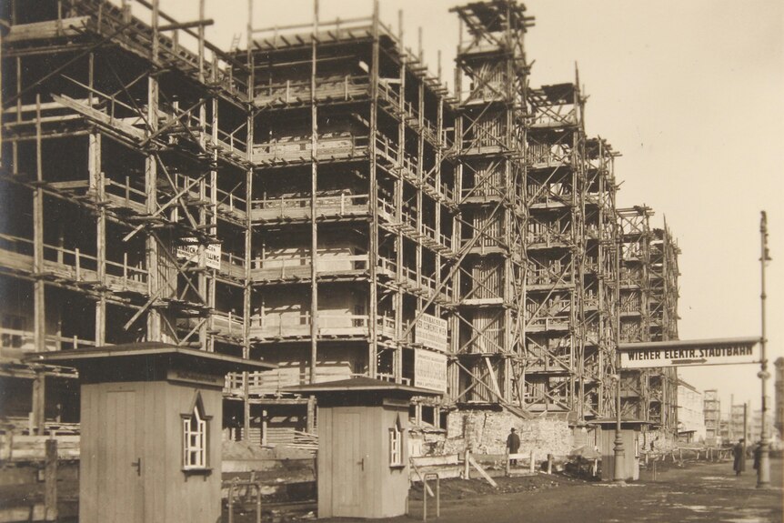 A 1920s sepia photograph of an apartment building construction site