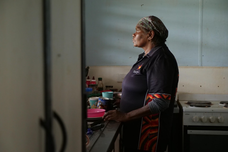 Eva looks out of the window as she stands in the kitchen