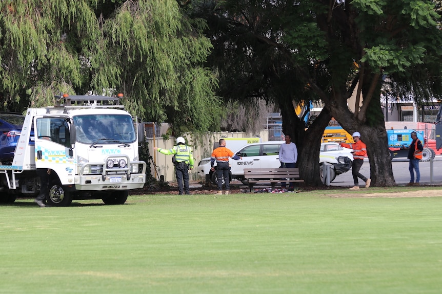 A tow truck and multiple people in high-vis at a park.